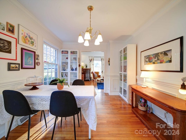 dining space featuring a wealth of natural light, an inviting chandelier, ornamental molding, and light hardwood / wood-style flooring