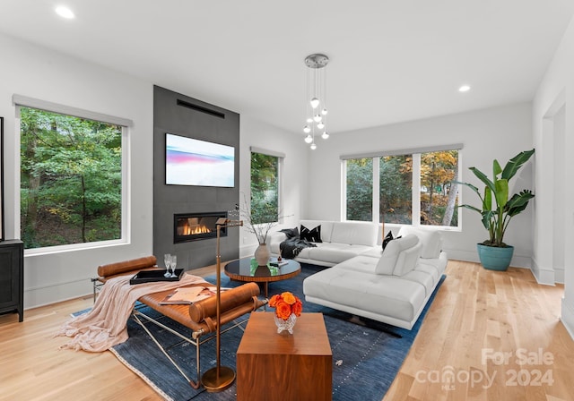 living room featuring a tiled fireplace, plenty of natural light, and light wood-type flooring