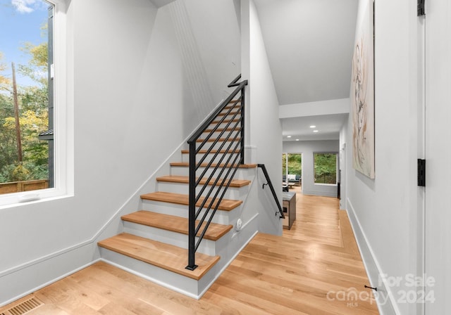 stairway featuring a wealth of natural light and hardwood / wood-style floors