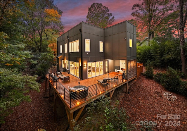 back house at dusk with a deck and an outdoor hangout area