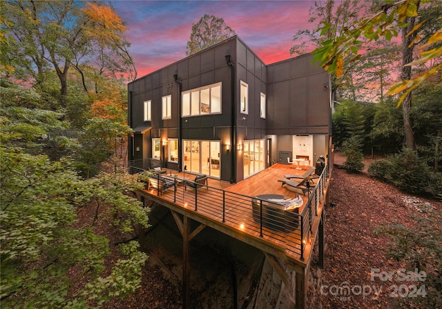 back house at dusk with a wooden deck