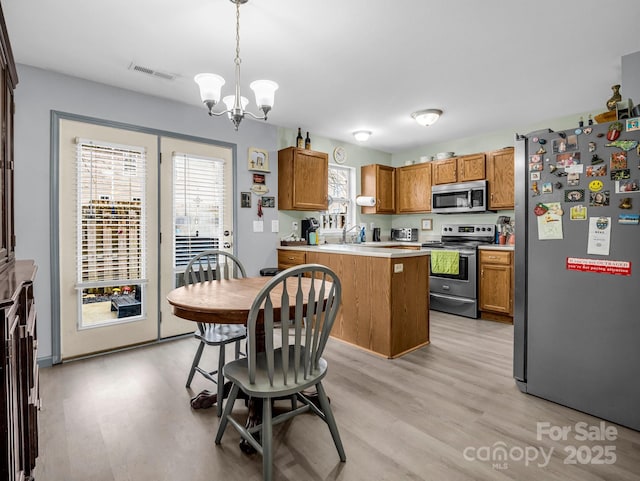 kitchen featuring decorative light fixtures, a wealth of natural light, appliances with stainless steel finishes, and an inviting chandelier