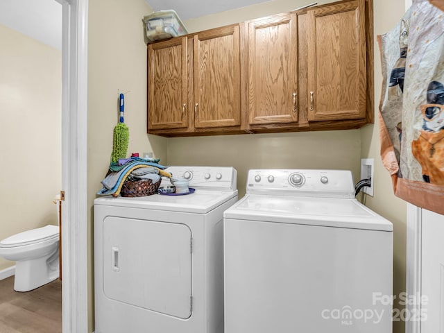 laundry room with cabinets, washing machine and dryer, and hardwood / wood-style flooring