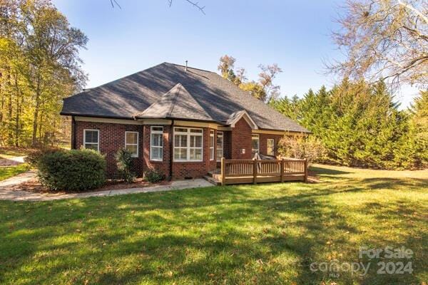 back of property with a deck and a yard