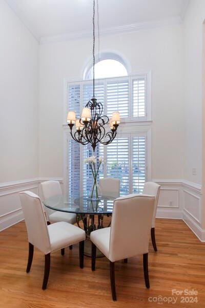 dining room featuring light wood-type flooring, an inviting chandelier, and ornamental molding