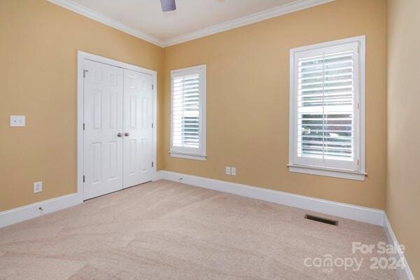 unfurnished bedroom featuring multiple windows, light carpet, crown molding, and ceiling fan