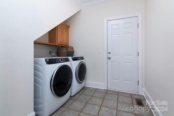 laundry room featuring washer and dryer, cabinets, light tile patterned floors, and crown molding