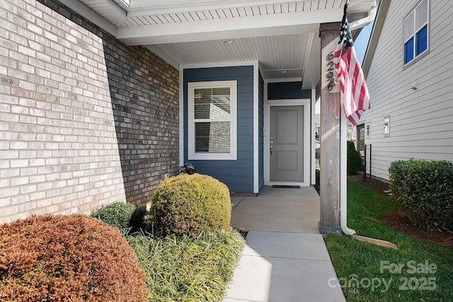 view of exterior entry featuring covered porch and brick siding