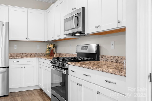 kitchen featuring light stone countertops, light wood-style flooring, white cabinetry, and stainless steel appliances