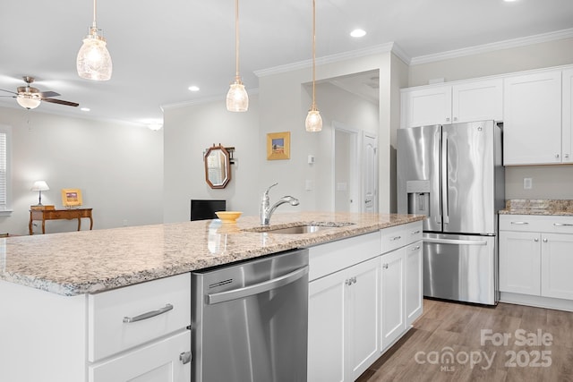 kitchen featuring stainless steel appliances, ornamental molding, light wood-type flooring, and a sink