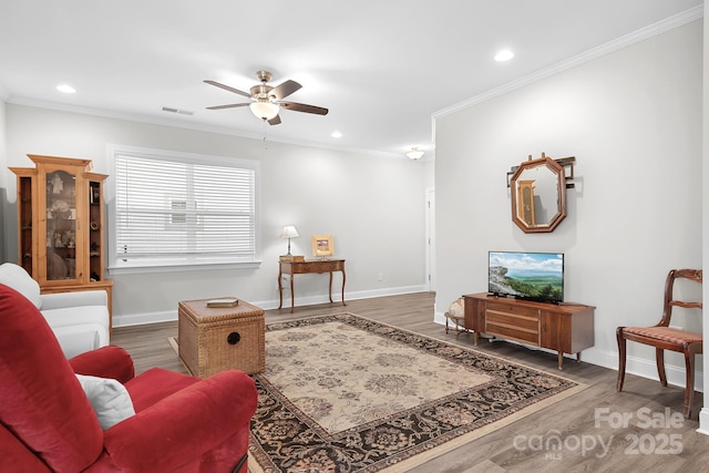 living room with baseboards, wood finished floors, visible vents, and crown molding