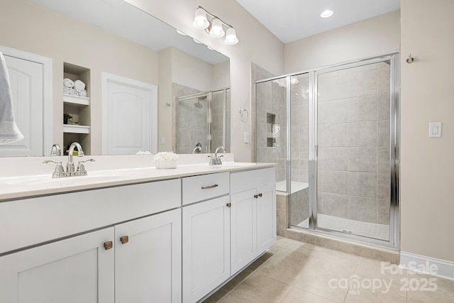 full bathroom featuring double vanity, a stall shower, tile patterned flooring, and a sink