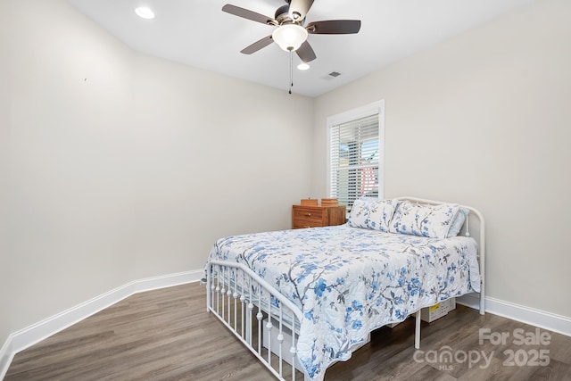 bedroom with wood finished floors, visible vents, and baseboards