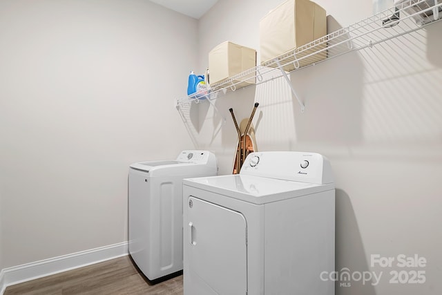 laundry area with laundry area, baseboards, washer and dryer, and wood finished floors