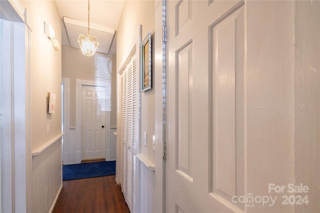 hall featuring dark wood-type flooring and a chandelier