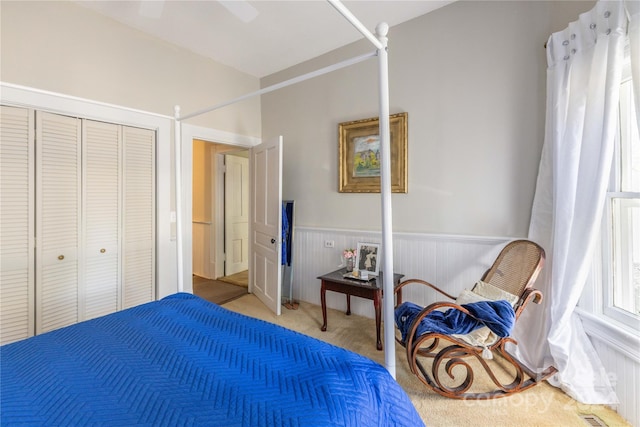 bedroom with a closet, wooden walls, carpet flooring, and ceiling fan