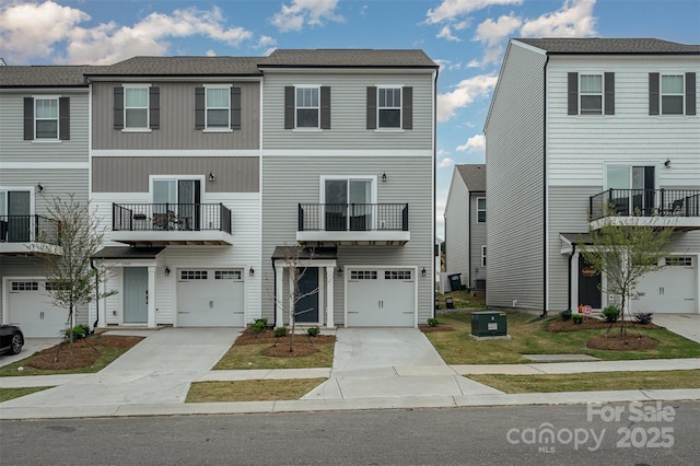 townhome / multi-family property featuring concrete driveway, central AC, and an attached garage