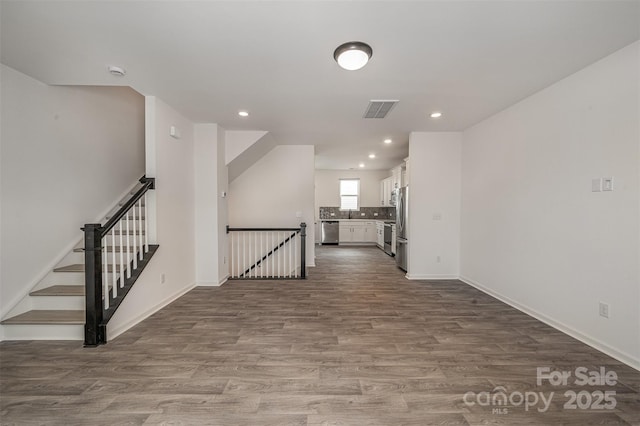 spare room featuring baseboards, visible vents, stairway, dark wood-style flooring, and recessed lighting