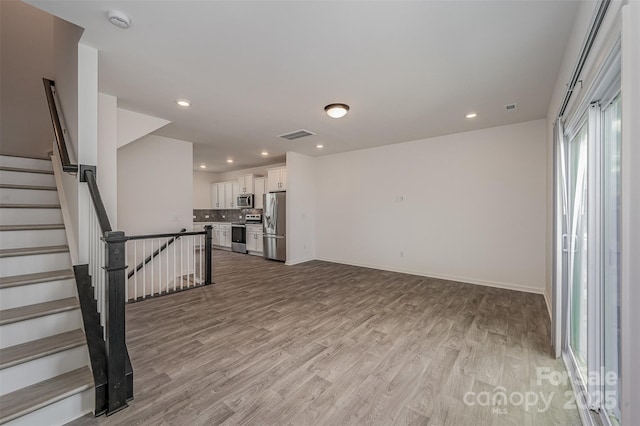 empty room featuring light wood-style flooring, visible vents, baseboards, and recessed lighting