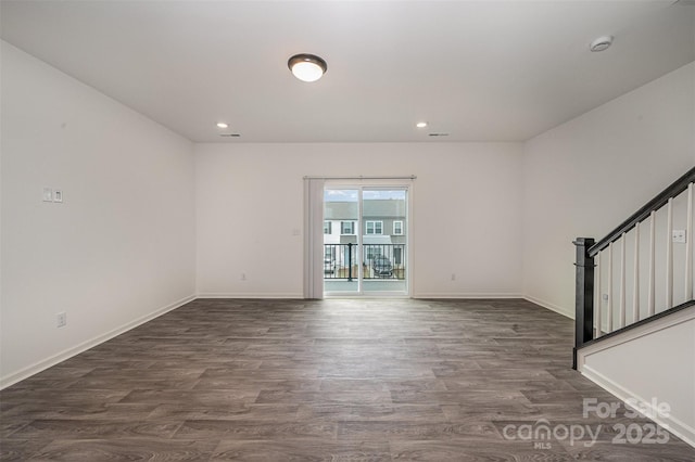 unfurnished room with stairs, dark wood-style flooring, and baseboards