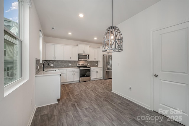 kitchen featuring dark wood-style floors, stainless steel appliances, light countertops, backsplash, and white cabinetry