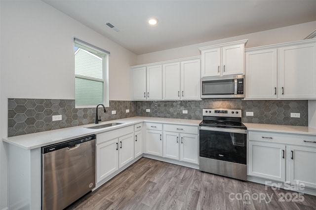 kitchen featuring light wood-style flooring, a sink, visible vents, white cabinetry, and appliances with stainless steel finishes