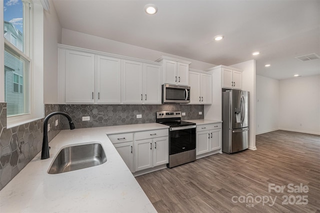 kitchen with appliances with stainless steel finishes, visible vents, a sink, and white cabinetry