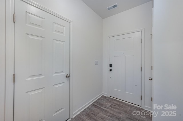 doorway featuring dark wood finished floors, visible vents, and baseboards