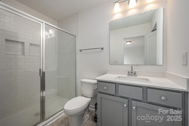 full bath featuring vanity, a shower stall, and toilet