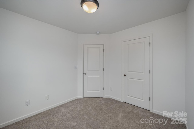 unfurnished room with carpet flooring and baseboards