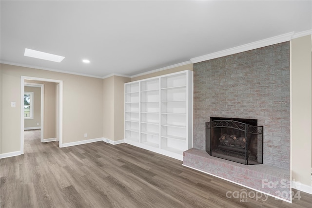 unfurnished living room with crown molding, a brick fireplace, hardwood / wood-style flooring, and a skylight