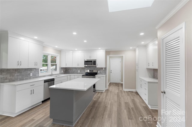 kitchen featuring light hardwood / wood-style flooring, stainless steel appliances, crown molding, a center island, and white cabinetry