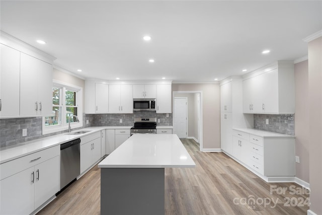 kitchen with a kitchen island, white cabinets, stainless steel appliances, and light wood-type flooring