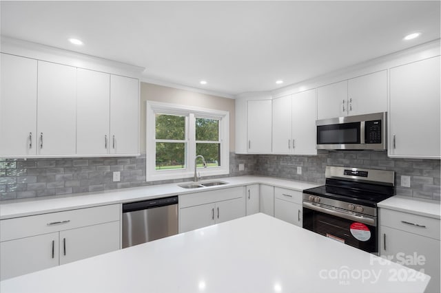 kitchen with appliances with stainless steel finishes, decorative backsplash, white cabinets, and sink