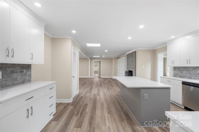 kitchen featuring tasteful backsplash, wood-type flooring, stainless steel dishwasher, and white cabinets