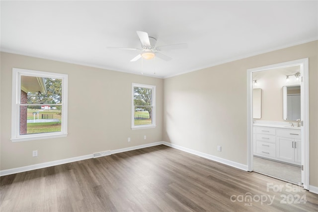 unfurnished bedroom with ensuite bathroom, ornamental molding, dark hardwood / wood-style floors, and ceiling fan