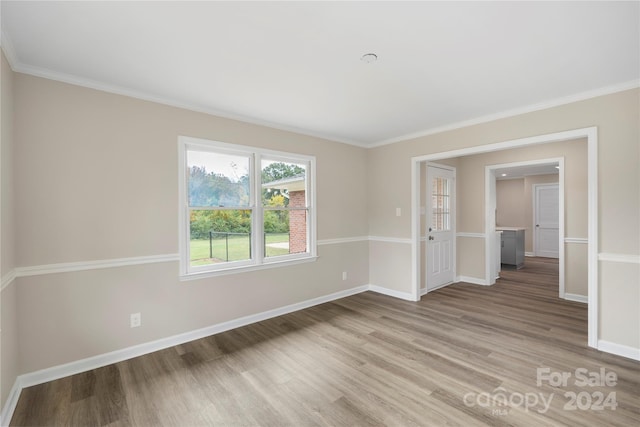 spare room with crown molding and light wood-type flooring