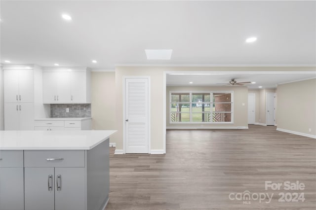 kitchen featuring decorative backsplash, crown molding, light wood-type flooring, and ceiling fan