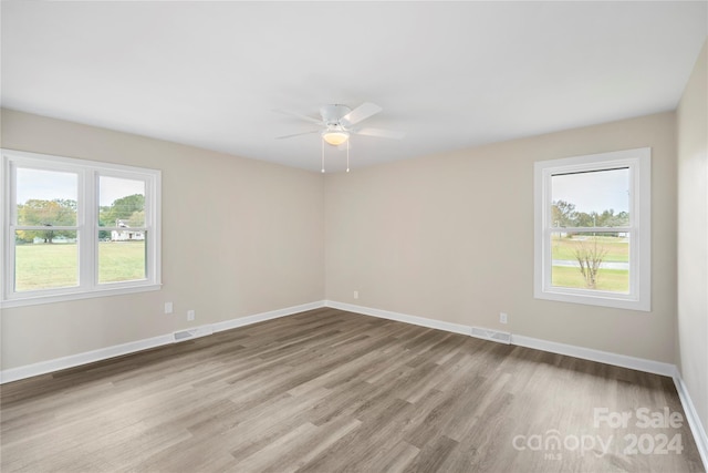 spare room featuring light hardwood / wood-style floors, a wealth of natural light, and ceiling fan