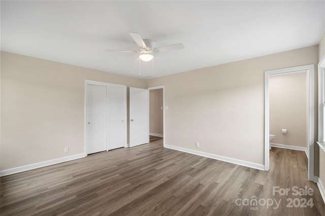 unfurnished bedroom featuring a closet, ensuite bath, wood-type flooring, and ceiling fan