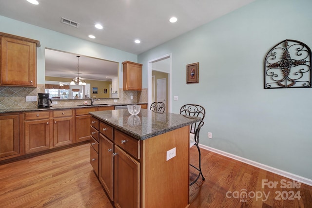 kitchen featuring a center island, light hardwood / wood-style floors, a breakfast bar area, and sink