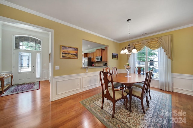 dining area featuring crown molding, light hardwood / wood-style floors, and a notable chandelier