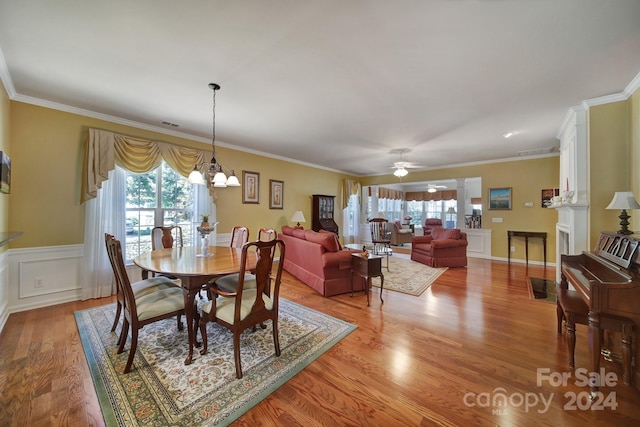 dining area featuring ceiling fan with notable chandelier, light hardwood / wood-style floors, and ornamental molding