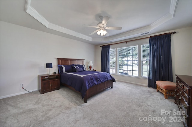 bedroom with a raised ceiling, ceiling fan, light colored carpet, and ornamental molding