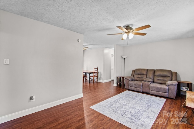 living room featuring ceiling fan, dark hardwood / wood-style floors, and a textured ceiling