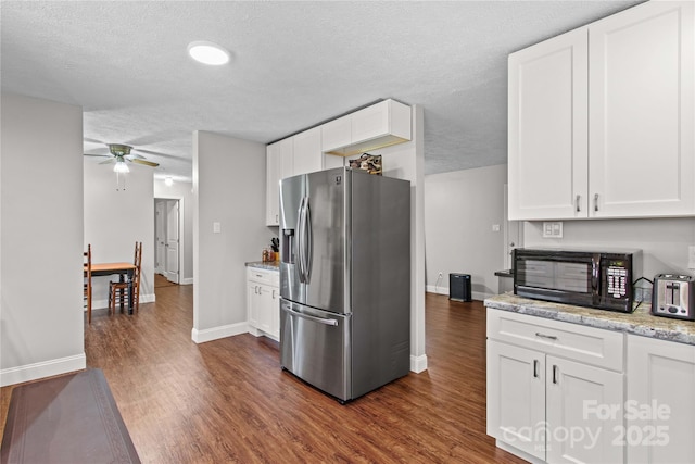 kitchen featuring stainless steel fridge, a textured ceiling, and white cabinetry