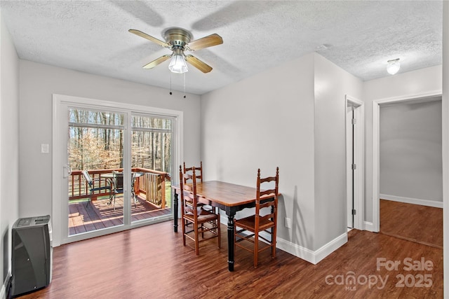 dining area with a textured ceiling, ceiling fan, and dark wood-type flooring