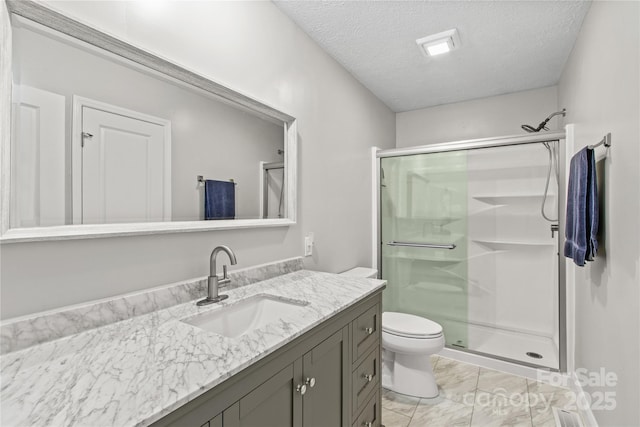 bathroom with vanity, toilet, a shower with door, and a textured ceiling