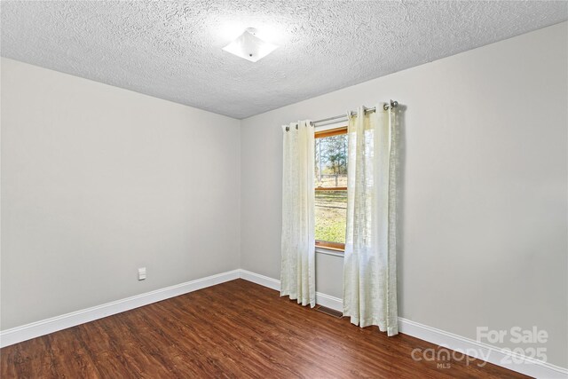 unfurnished room featuring a textured ceiling and dark hardwood / wood-style floors