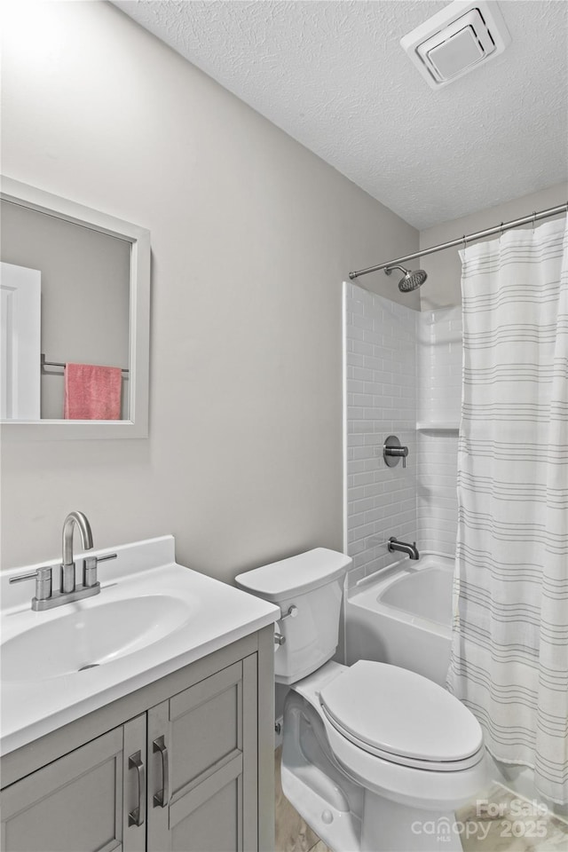 full bathroom featuring shower / tub combo with curtain, vanity, a textured ceiling, and toilet